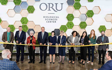 Picture of a row of People Cutting the Ribbon during the Ribbon Cutting Ceremony in front of the ORU's new biological sciences cener.